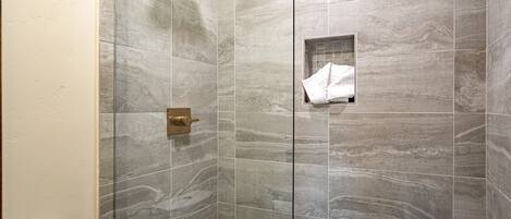 A shower with a glass door and a towel rack.