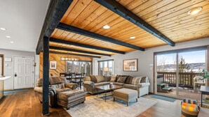 A spacious living room with a wooden ceiling, large windows, and a view of the outdoors. - Winterset 3 3 Bedroom Condo by RedAwning (Steamboat Springs)