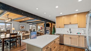 A modern kitchen with wooden cabinets, a central island, and a dining area with a view. - Winterset 3 3 Bedroom Condo by RedAwning (Steamboat Springs)