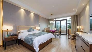 A hotel room with a large bed, bedside tables, a desk, and a view of the outdoors.
