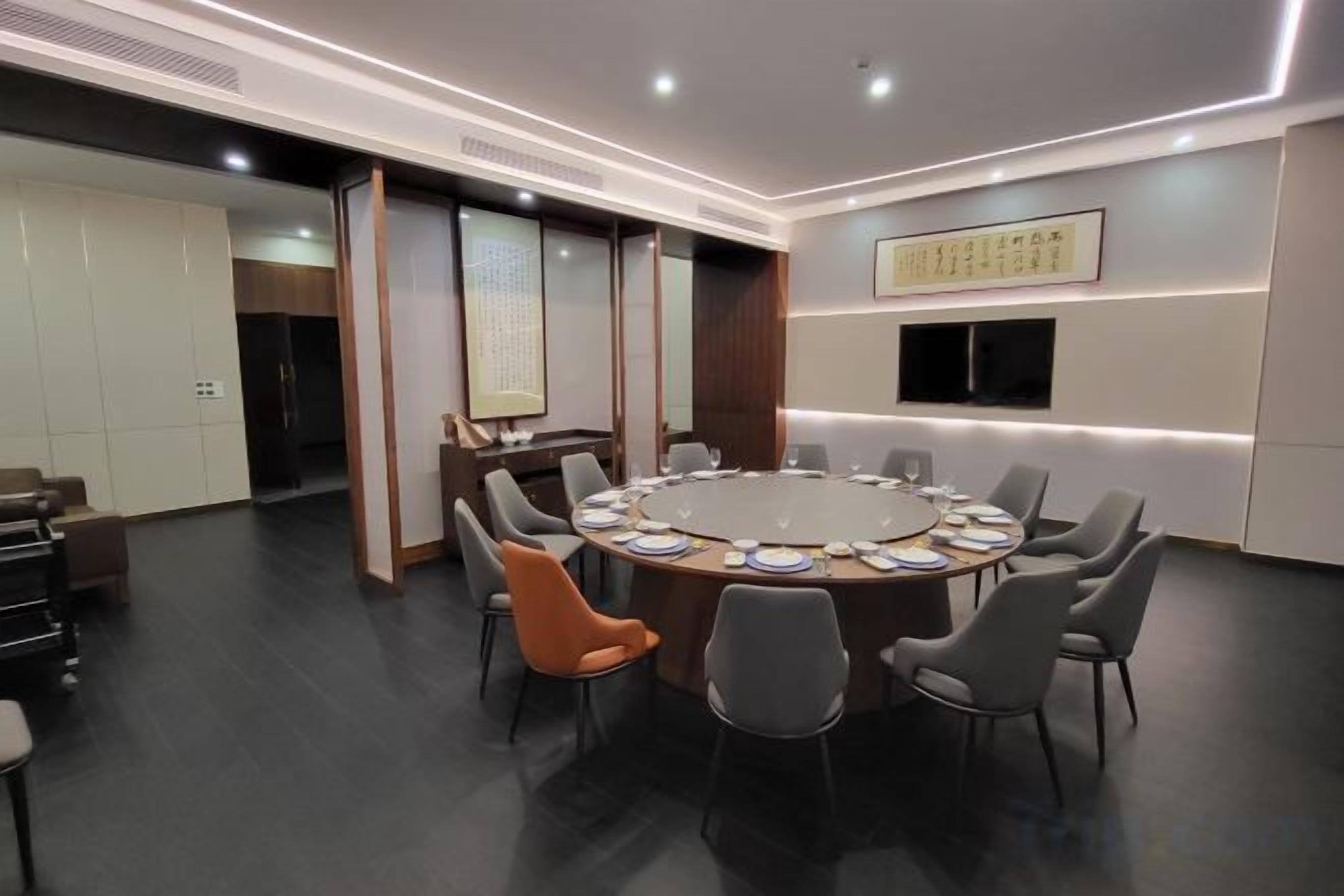 A conference room with a round table, multiple chairs, and a television screen on the wall.