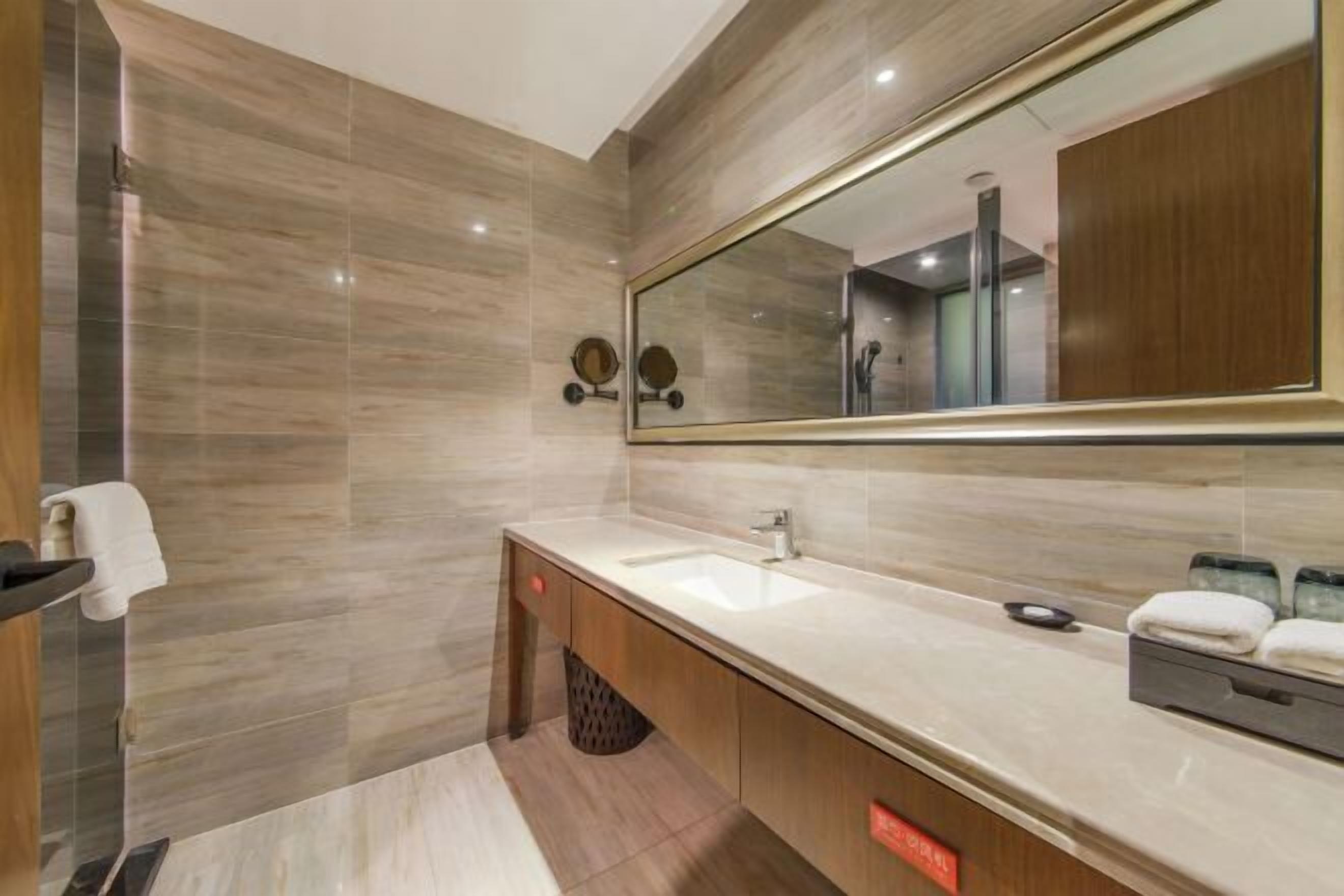 A modern bathroom with a large mirror, a sink, and a shower area.