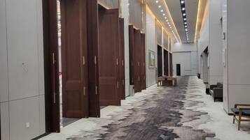 A hallway with wooden doors, a patterned carpet, and a bench.