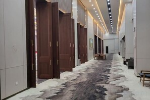 Un pasillo con puertas de madera, alfombra estampada y un banco.