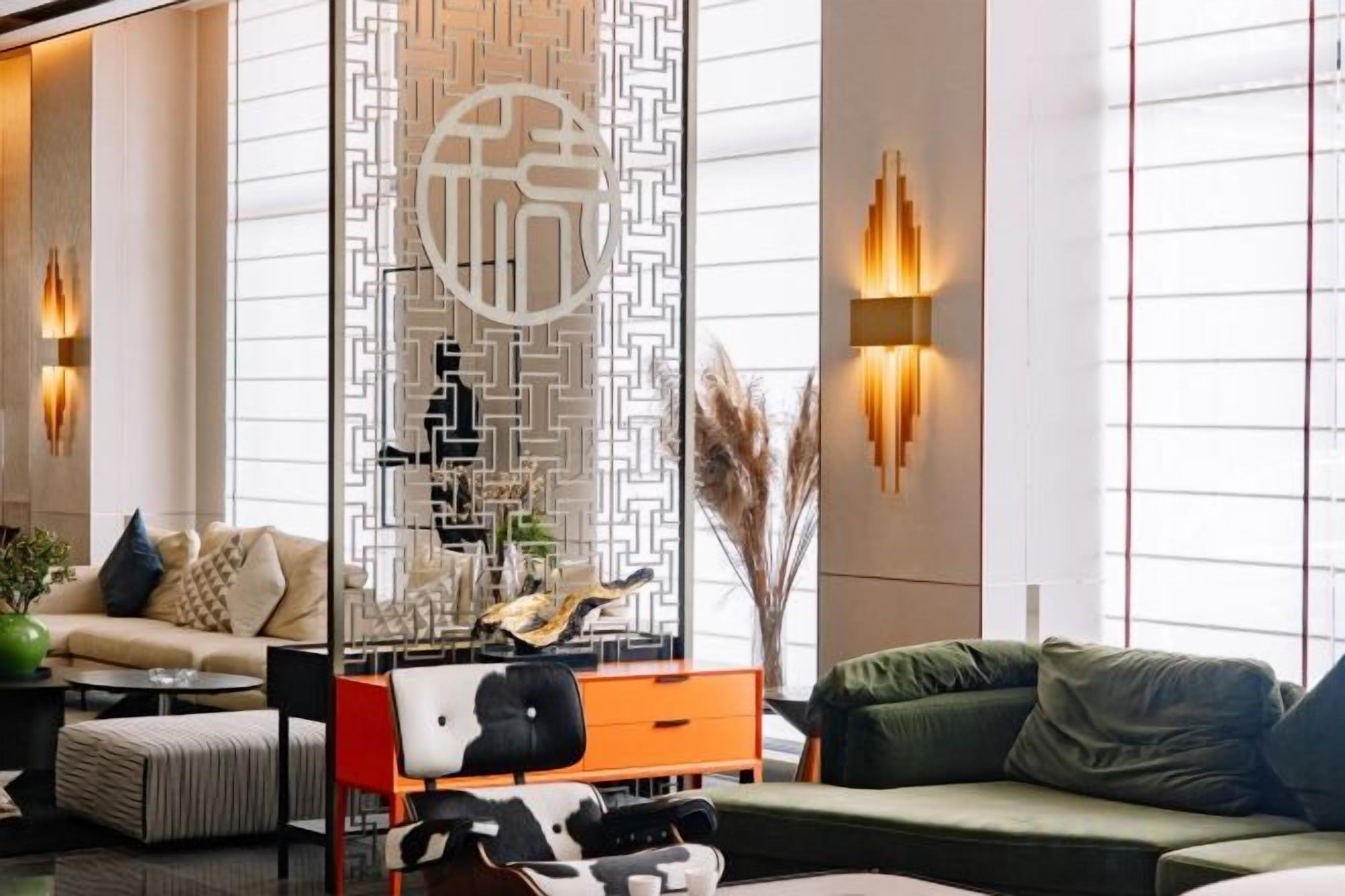A modern hotel lobby with a sofa, a coffee table, and a decorative wall with a geometric pattern.