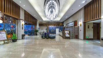 A spacious lobby with a modern chandelier, seating areas, and a reception desk.