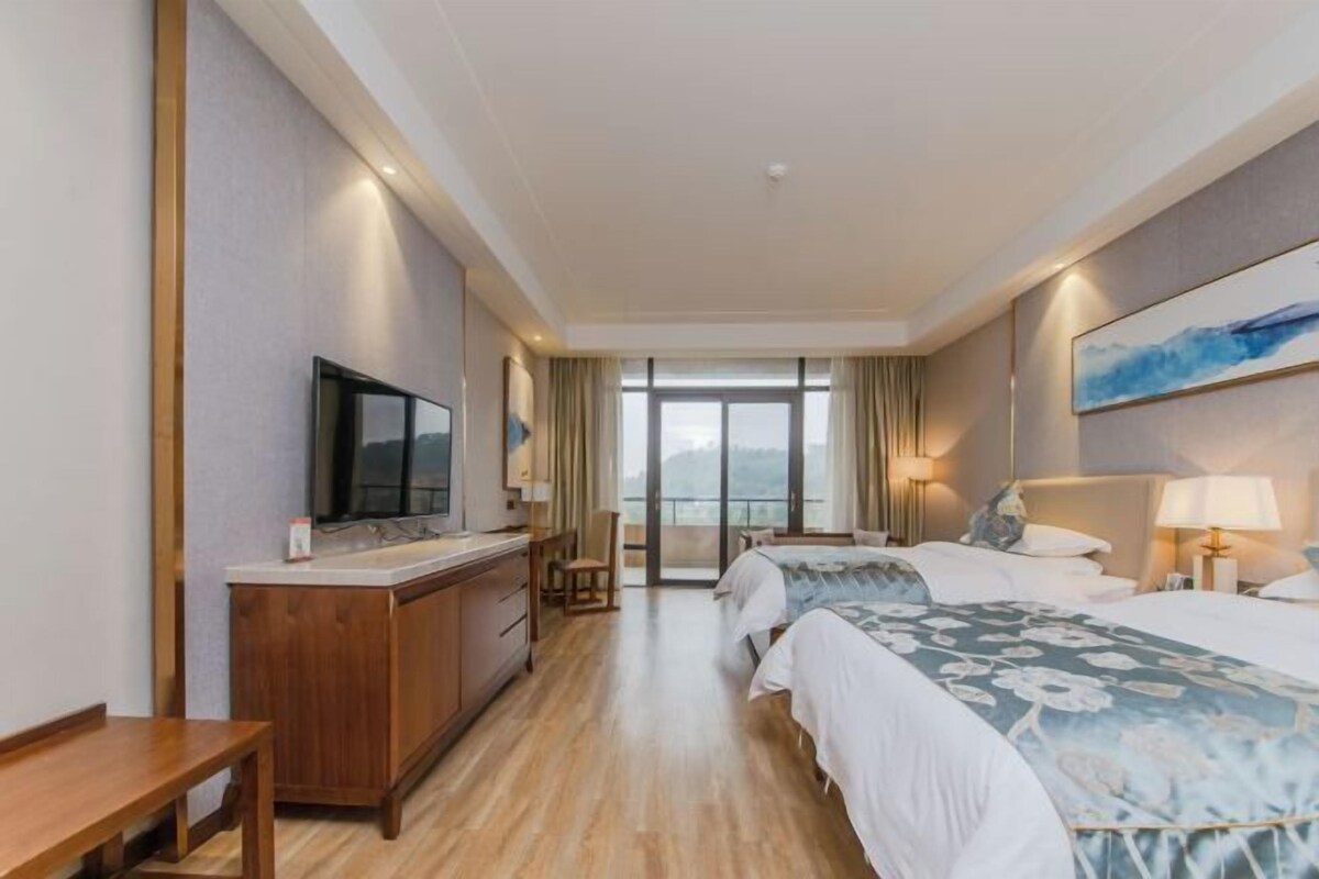 Ein Hotelzimmer mit Bett, Nachttisch, Fernseher und Blick ins Freie.
