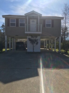 A two-story house with a balcony, a garage, and a tree in front. - Riverfront Hideaway (Gulfport)
