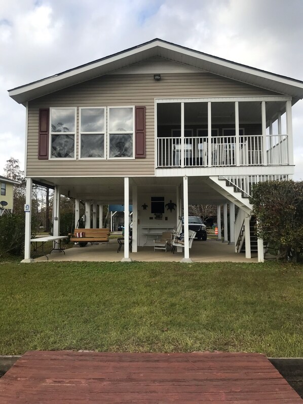 A two-story house with a covered porch, a staircase to the upper level, and a small outdoor seating area. - Riverfront Hideaway (Gulfport)