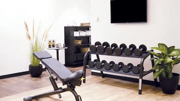 A gym with exercise equipment, a TV, and potted plants.