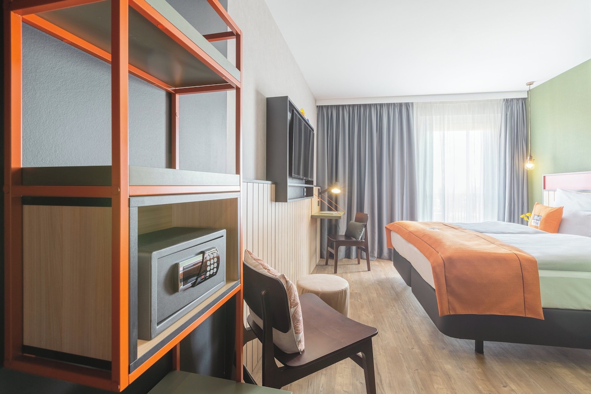 Une chambre d’hôtel comprenant un lit, un bureau avec une chaise, une télévision et un minibar.