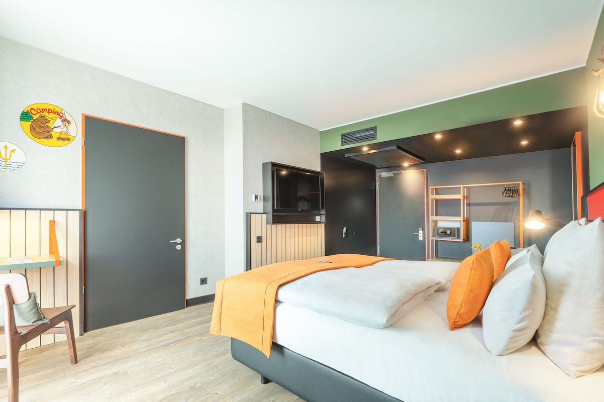 Une chambre d’hôtel moderne équipée d’un lit, d’un bureau et d’une télévision.