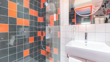 A bathroom with a glass shower enclosure, a white sink, and a mirror.