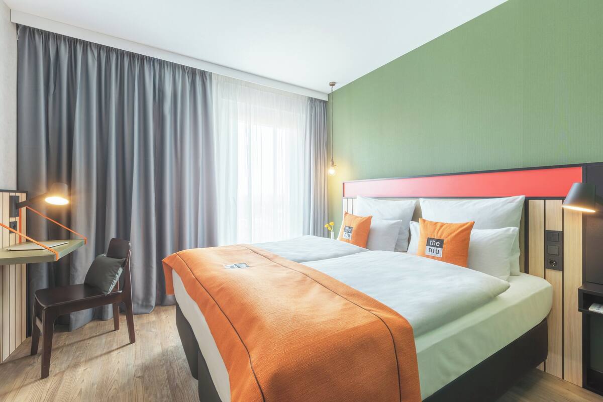 A hotel room with a bed, a desk, and a chair.