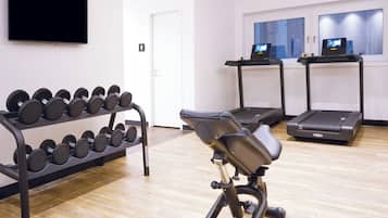 A gym with exercise equipment including dumbbells, a stationary bike, and treadmills.