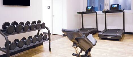 A gym with exercise equipment including dumbbells, a stationary bike, and treadmills.