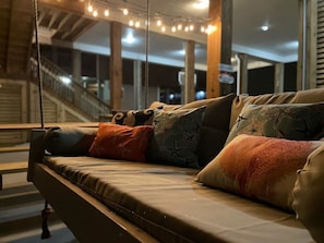 Un sofá con varios cojines en una habitación con vista a una escalera y un cartel al fondo.