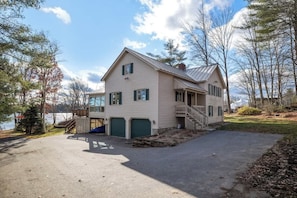 A two-story house with a covered porch, a garage, and a view of a lake. - Halfmoon Lake 4BR Home w Game Room, Deck, Dock! (Alton)