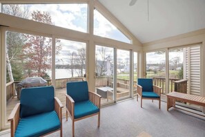 A sunroom with large windows, a wooden deck, and outdoor seating. - Halfmoon Lake 4BR Home w Game Room, Deck, Dock! (Alton)