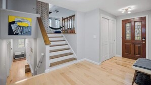 Um interior moderno com uma escada, um banco de madeira e uma porta com painéis de vidro.