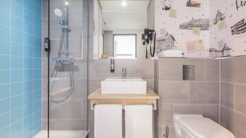 A bathroom with a glass-enclosed shower, a wooden vanity with a sink, and a toilet.