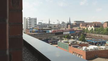 A cityscape with a train passing over a bridge, buildings, and construction cranes.