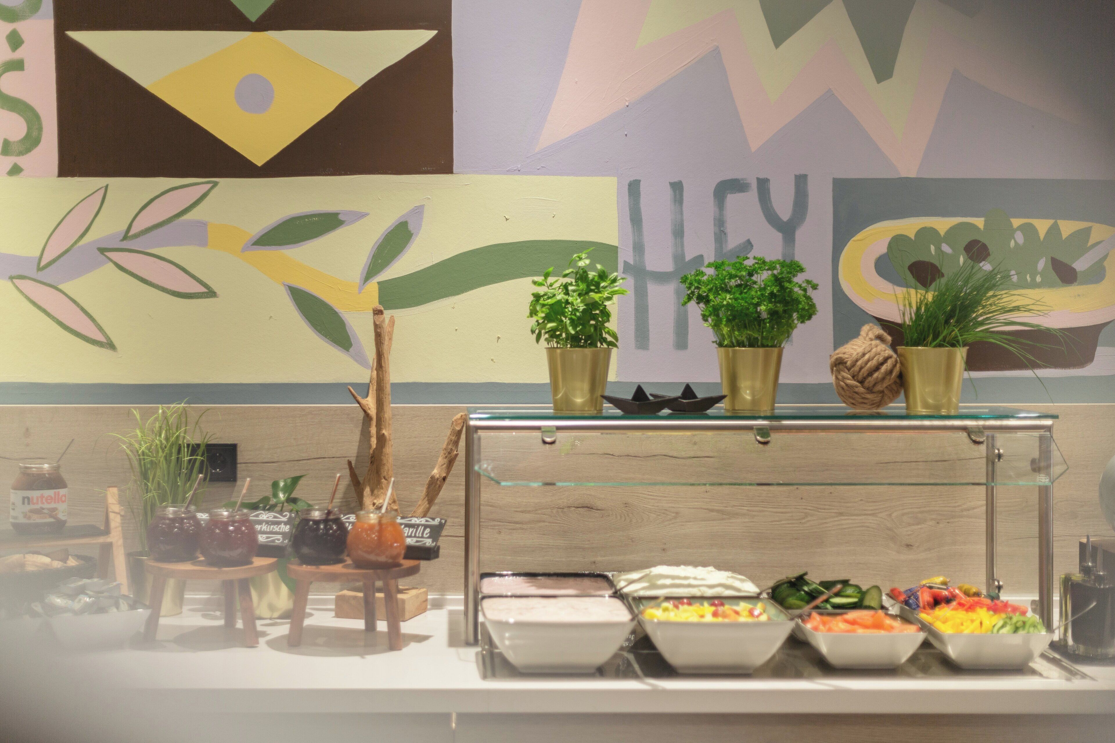 A buffet area with various food items and decorative plants.