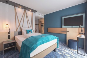 A modern hotel room with a bed, bedside tables, a desk, a chair, a TV, and a trash bin. - Holiday Inn - the niu, Yen Hamburg City by IHG (Hamburg)