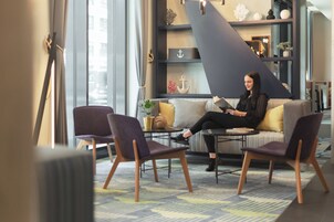 Ein modernes Interieur mit einer Couch, zwei Sesseln, einem kleinen Tisch und Dekorationselementen.