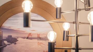 A framed picture of a sunset over a river with buildings, and a light fixture with bulbs.