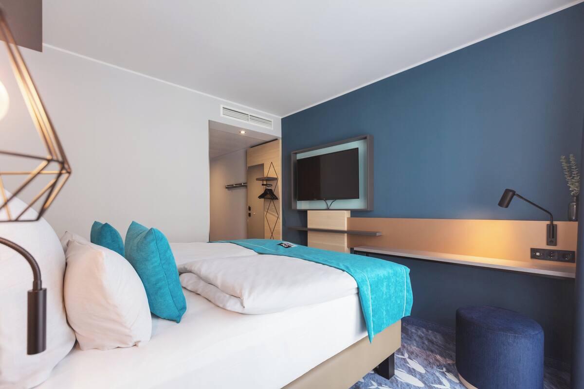 Una habitación de hotel moderna con una cama, un televisor, un escritorio y una silla.