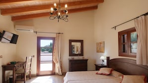 Un dormitorio con cama, escritorio, silla, cómoda, espejo y ventana con cortinas.