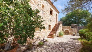 Un edificio de piedra con un patio, plantas en macetas y una escalera que lleva a un nivel superior.