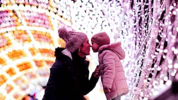 A couple embracing in a festive setting with decorative lights.
