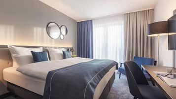 Habitación de hotel con una cama grande, un escritorio con una silla, una lámpara y un televisor.