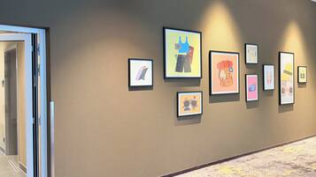 A hallway with framed artwork on the wall and a carpeted floor.