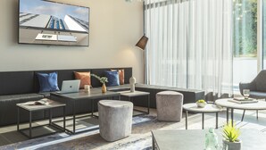 Una sala de estar moderna con sofá, mesa de centro, reposapiés y televisor de pantalla plana montado en la pared.