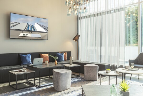 Una sala de estar moderna con sofá, mesa de centro, reposapiés y televisor de pantalla plana montado en la pared.