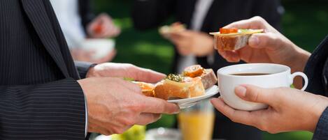 Un grupo de personas en un bufé, con comida y una taza de café.