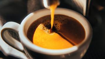 A cup of coffee with a spoon on the side.