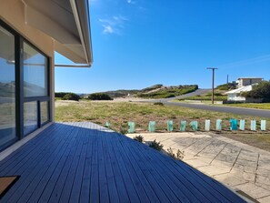 Une terrasse en bois offrant une vue dégagée sur une route et sur des collines lointaines.