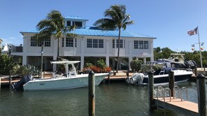 A waterfront property with a large white building, docked boats, and a clear blue sky. - Keys Deal w/Cafe & Pool Bar! Up to 20% Off Oceanfront 2/2 with Private Beach (Tavernier)