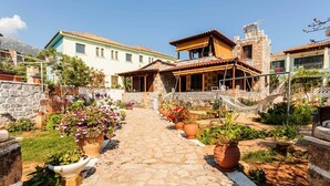 A courtyard with a stone pathway leading to a building with a tiled roof and a hammock.