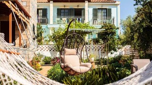 A hammock chair in a garden with a building in the background.