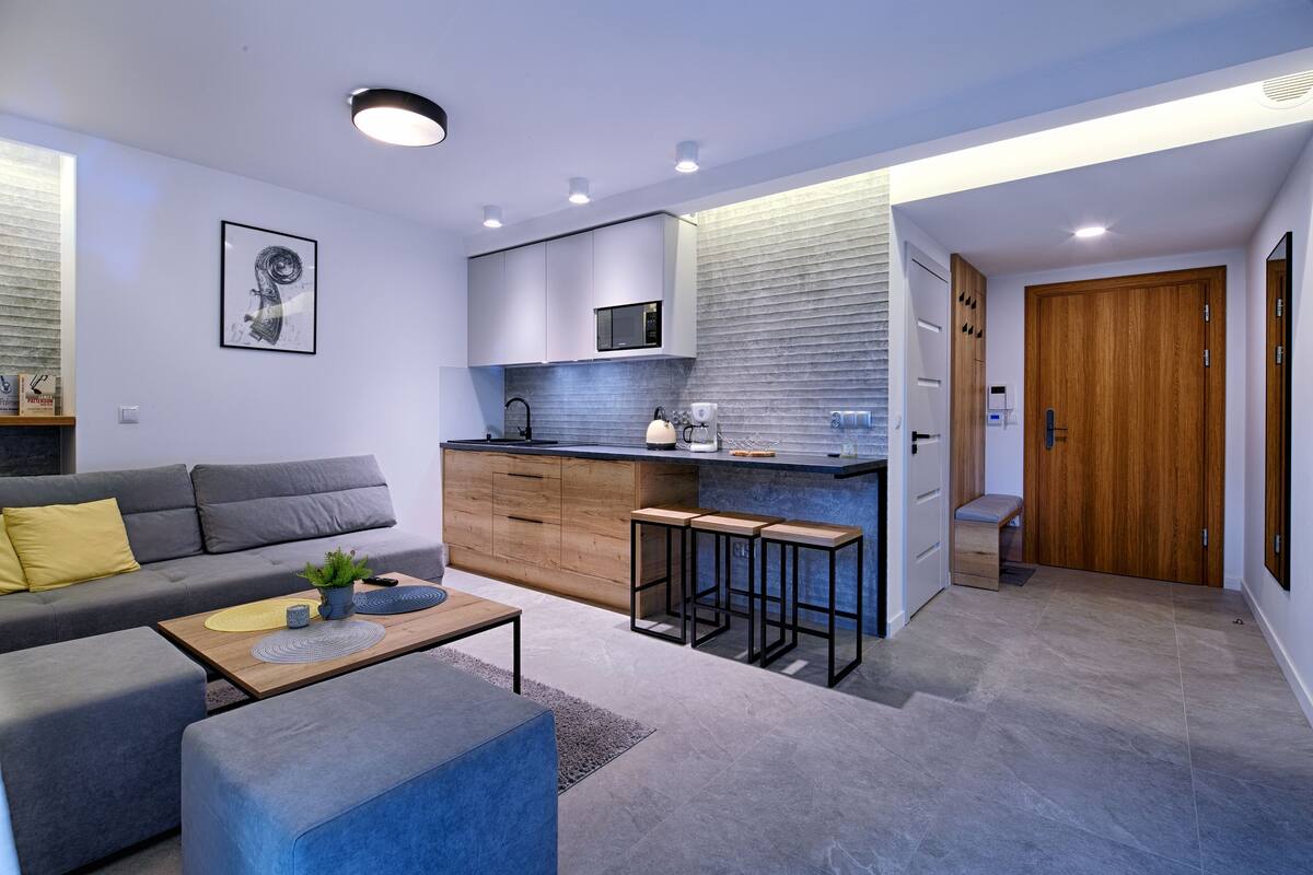 A modern kitchen with a built-in microwave, wooden cabinets, and a bar area with stools.