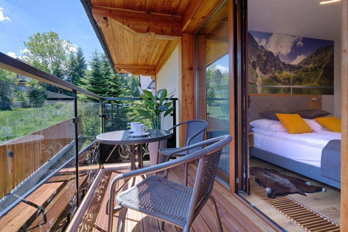 A balcony with wicker chairs, a table, and a view of a mountain landscape.