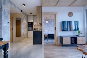 Un intérieur moderne comprenant une cuisine, un coin repas et une chambre avec télévision.