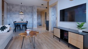 A modern living room with a dining area, a large flat-screen TV mounted on the wall, and a wooden ceiling. - Antałówka 12 Apartamenty wysoki standard (Zakopane)