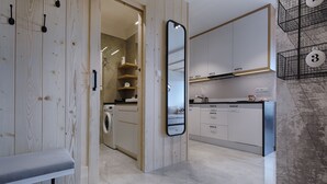 A modern kitchen with white cabinets, a large mirror, and a wooden door. - Antałówka 12 Apartamenty wysoki standard (Zakopane)