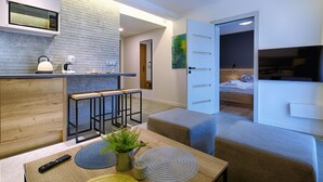 A modern hotel room with a kitchenette, a dining area, and a bedroom. - Antałówka 12 Apartamenty wysoki standard (Zakopane)